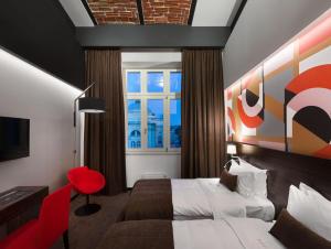 une chambre d'hôtel avec un lit et un tabouret rouge dans l'établissement BANKHOTEL, à Lviv