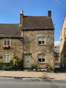 a brick house with a green door on a street at St Antony's Cottage in Stow on the Wold