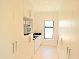 a kitchen with white cabinets and a microwave at OCEAN BREEZE SUNSET BEACH - Cape Town in Cape Town