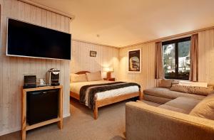 GsteigにあるHotel Sanetschのベッド1台、薄型テレビが備わるホテルルームです。