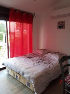 LédenonにあるGite les Coquelicotsのベッドルーム1室(赤いカーテン付きのベッド1台付)