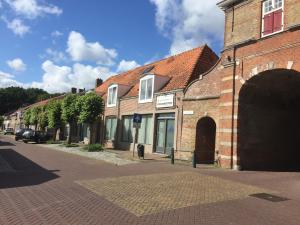 uma rua com um edifício de tijolos com um arco em Residence De Kaaipoort appartementen em Aardenburg