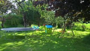 a playground with a trampoline and swings in the grass at gîte du Clos Sébastien in Beautheil