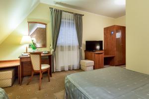 タルヌフにあるHotel Krzyskiのベッド、デスク、テレビが備わるホテルルームです。