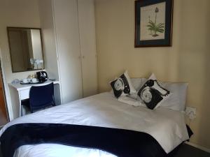 a bedroom with a white bed with black and white pillows at Fernrez@363 in Johannesburg