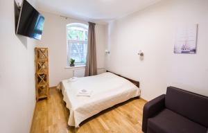 een kleine kamer met een bed en een bank bij Red Brick Apartments in Klaipėda