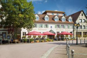 een groot gebouw met tafels en rode parasols voor het bij Flair Hotel Weinstube Lochner in Bad Mergentheim
