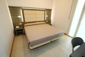 a small bedroom with a bed and a table at Hotel Boom in Rimini