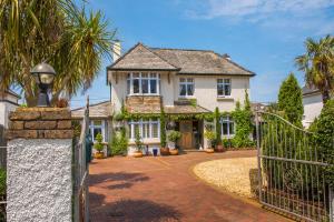 uma casa branca com um portão e uma entrada em Bradleigh Lodge em St Austell