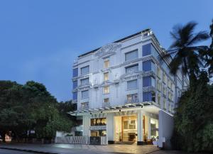 a white building with a palm tree in front of it at La Marvella, Bengaluru in Bengaluru