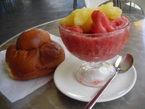 a glass bowl of fruit on a plate with a bread at B&B CasAnsaldo in Giarre