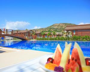 eine Schale Obst auf einem Tisch neben einem Pool in der Unterkunft Sedir Park - Beach Bungalow in Kargıcak