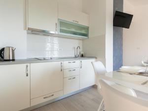 una cucina con armadi bianchi e tavolo con sedie di Lavish Apartment in Omi alj with Rooftop Terrace a Omišalj (Castelmuschio)