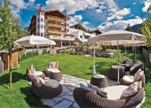 a patio with chairs and tables and umbrellas at Hotel Al Sonnenhof in San Vigilio Di Marebbe