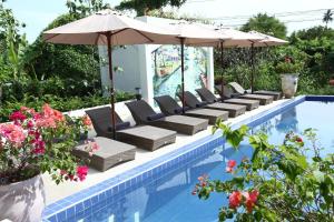 a pool with chairs and umbrellas next to a pool at Villa Amphawa in Amphawa