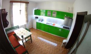 una cocina con armarios verdes y una mesa con sillas en Penzion pod vejmutovym lesom, en Kremnica