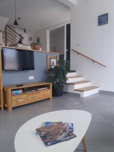 ein Wohnzimmer mit einem TV, einem Tisch und einer Treppe in der Unterkunft Villa Belitzein with swimming pool in Šibenik