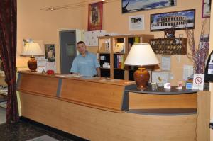 a man standing at a counter in a store at Citotel Hôtel Cesar in Nîmes