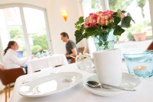 a table with a vase of flowers and a plate with a cup at Villa Baltia in Graal-Müritz