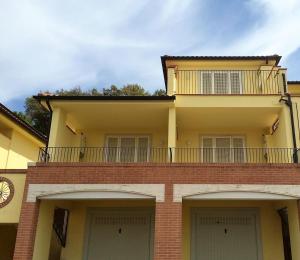 um edifício com duas portas de garagem e uma varanda em Residenza la Gioiosa. em Scarlino
