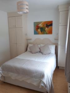 a bedroom with a white bed with a painting on the wall at Inisfail in Killarney