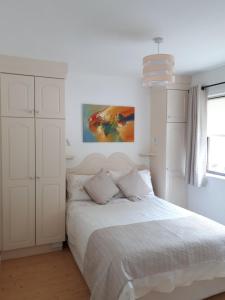 a white bedroom with a bed and a painting on the wall at Inisfail in Killarney