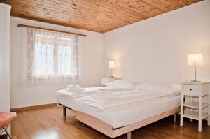 - une chambre blanche avec 2 lits et un plafond en bois dans l'établissement Apartment Aare 3.5 by GriwaRent AG, à Goldswil