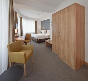 una camera d'albergo con letto, sedia e armadietto di City Hotel a Lussemburgo