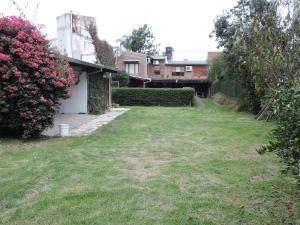einen Hof mit einem Haus und rosa Rosen in der Unterkunft Cerros de Salta in Salta