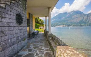 a house by the water with a table and chairs at La Punta Apartment in Bellagio