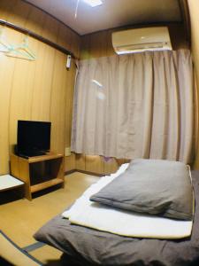 a bedroom with a bed and a window with a television at Ryokan Nakadaya in Tokyo