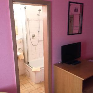 a bathroom with a tub and a shower with a television at Pension Mona Lisa in Munich