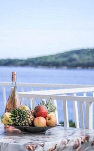 a plate of fruit on a table with a bottle of wine at Villa Marija - Sea View Rooms in Molunat