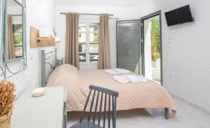 1 dormitorio con cama con sábanas rosas y silla en Syros INN, en Galissas