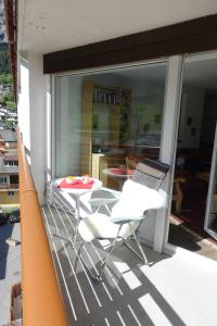 einen Balkon mit 2 Stühlen, einem Tisch und einem Fenster in der Unterkunft Studio Willimann Haus Dala im 4 Stock in Leukerbad