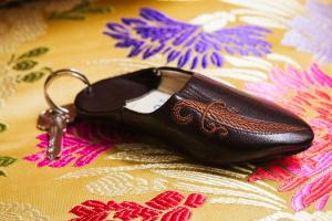 un paio di scarpe nere con una chiave su una coperta di Riad Naila & suite a Fes
