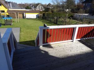 a deck with a red fence and a playground at Ferienhaus Koenigsberg Haus 1 in Scharbeutz