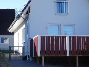 a white house with a wooden deck next to it at Ferienhaus Koenigsberg Haus 1 in Scharbeutz