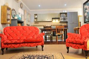 a living room with two red chairs and a kitchen at Versailles Self-Catering in Wellington