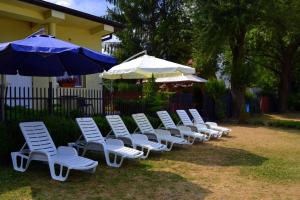 オクニンカにある"Vanilla" Pokoje i Apartamenty Nad Brzegiem Jezioraの白い芝生の椅子と傘の列