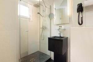 une salle de bain avec une douche en verre et un lavabo dans l'établissement Le Relais du Marais, à Paris 18 autres photos