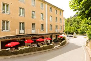 a building with red umbrellas in front of a building at Logis Hôtel de la Paix in Saint-Nectaire