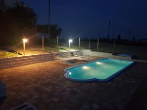 a swimming pool at night with a bench and lights at Il Gelso in Morrovalle