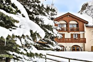 una casa ricoperta di neve di fronte agli alberi di Hôtel Saint-Martin a Saint-Martin-de-Belleville