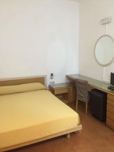 een slaapkamer met een bed, een bureau en een spiegel bij Hotel Villa Marina in La Maddalena