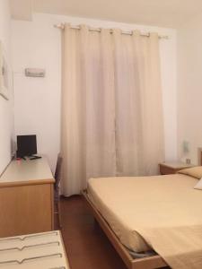 Cette chambre comprend deux lits, un bureau et un rideau. dans l'établissement Hotel Villa Marina, à La Maddalena