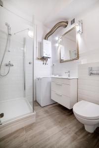 La salle de bains blanche est pourvue d'une douche, de toilettes et d'un lavabo. dans l'établissement Dziesiątka, à Olsztyn
