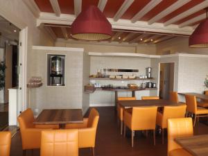 a restaurant with tables and chairs and a kitchen at Hotel Restaurant Le Parc in Moulins