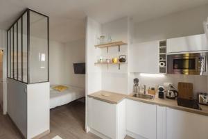 ニースにあるNicelidays - Le Berlioz - city central - 7min from beachesの白いキャビネット付きのキッチン、ベッド1台が備わる客室です。