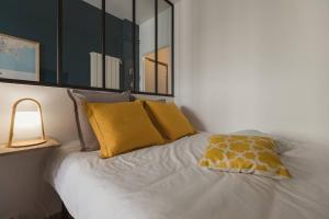 1 cama con 2 almohadas amarillas y espejo en Nicelidays - Le Berlioz - city central - 7min from beaches en Niza